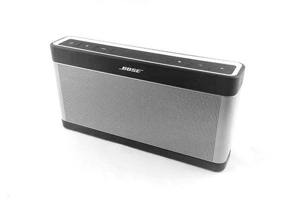 Hands pressing the power button on a Bose SoundLink speaker to initiate reset.