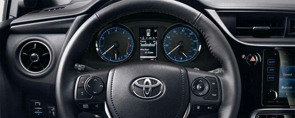 A hand pressing the odometer stem to select Trip A on the dashboard.