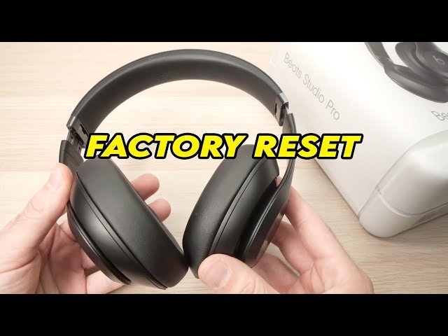 Fingers pressing the specific control buttons on wireless headphones during a factory reset process.