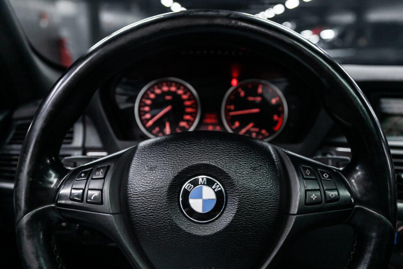 A person pressing the odometer button on a BMW dashboard to initiate a reset.