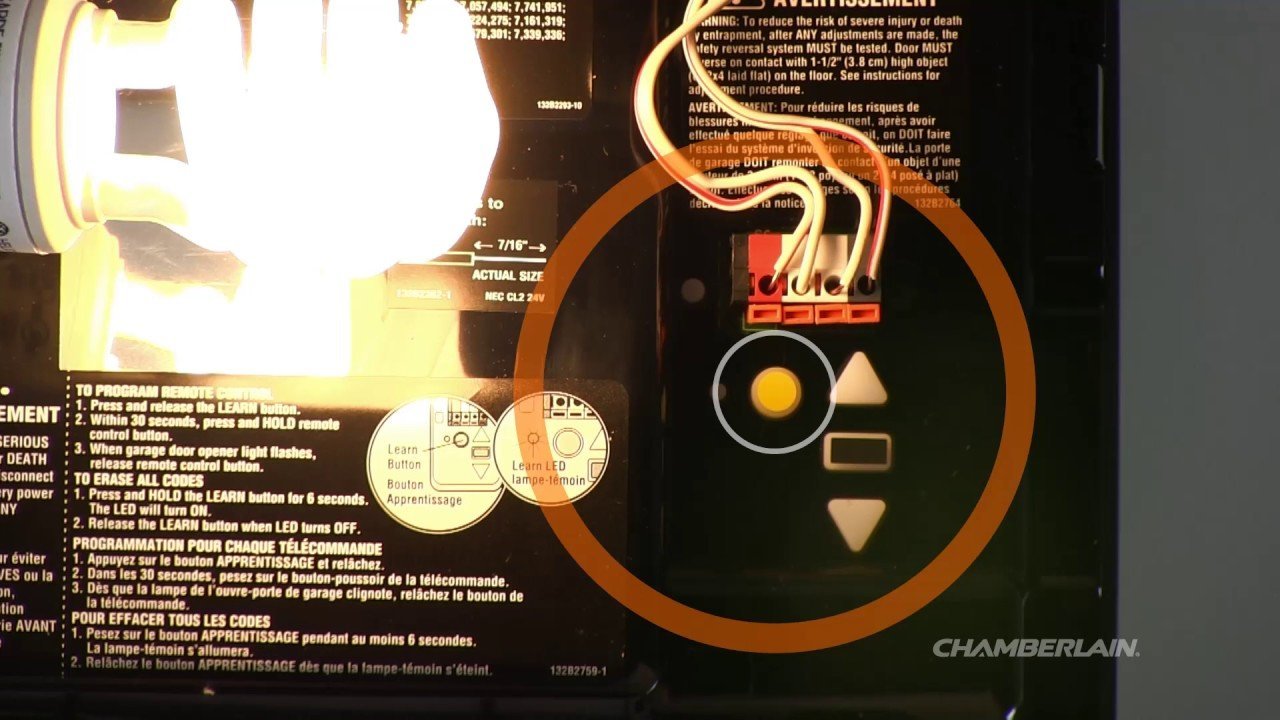 A close-up view of the yellow learn button on a Chamberlain garage opener.