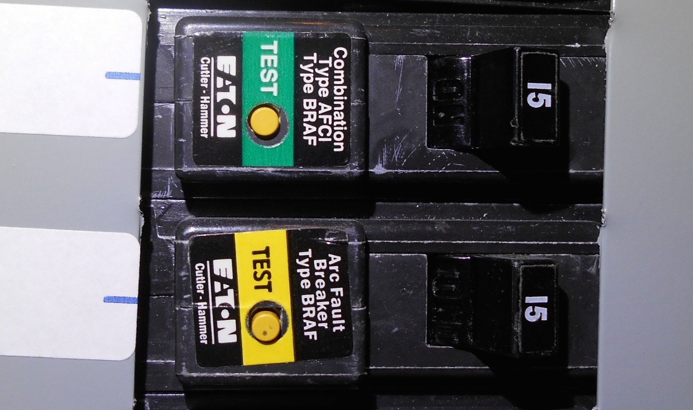 A hand reaching toward a circuit breaker inside a residential load center.