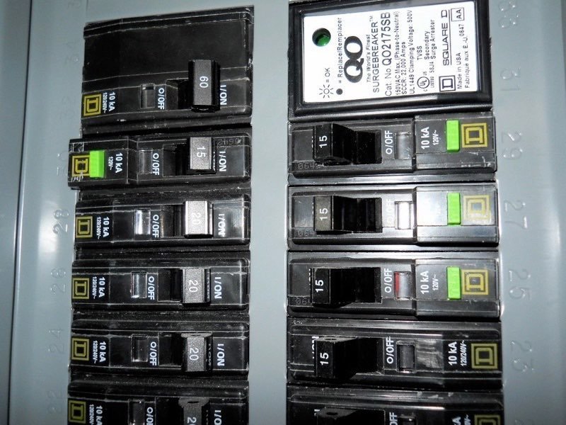 A voltage tester being used to perform a safety check on breakers.