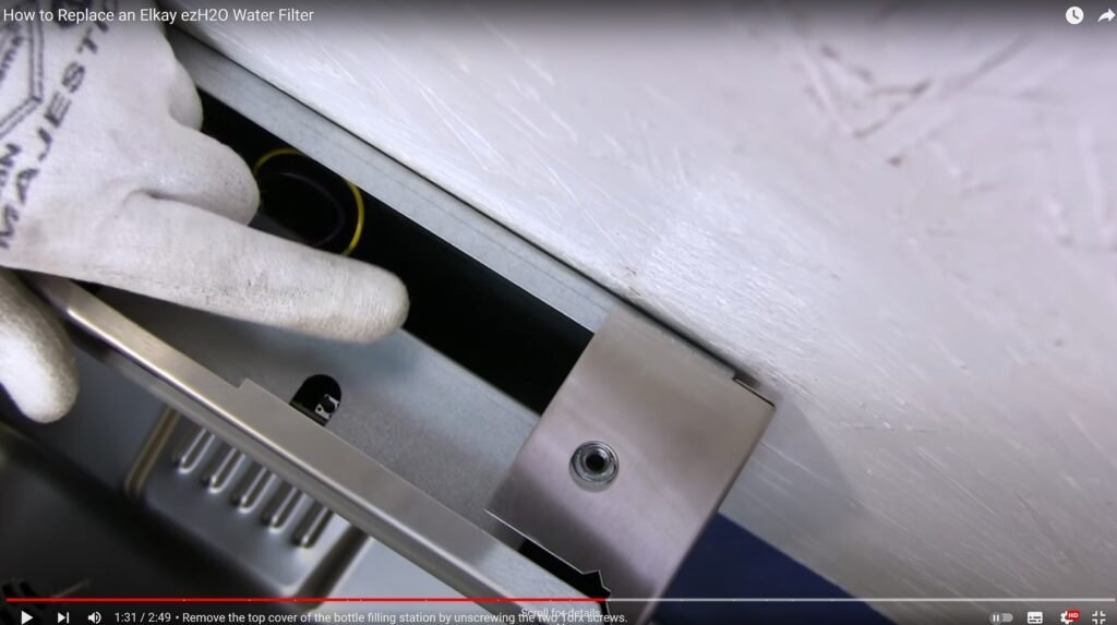 Hands using a screwdriver to access the internal reset button on a water station.