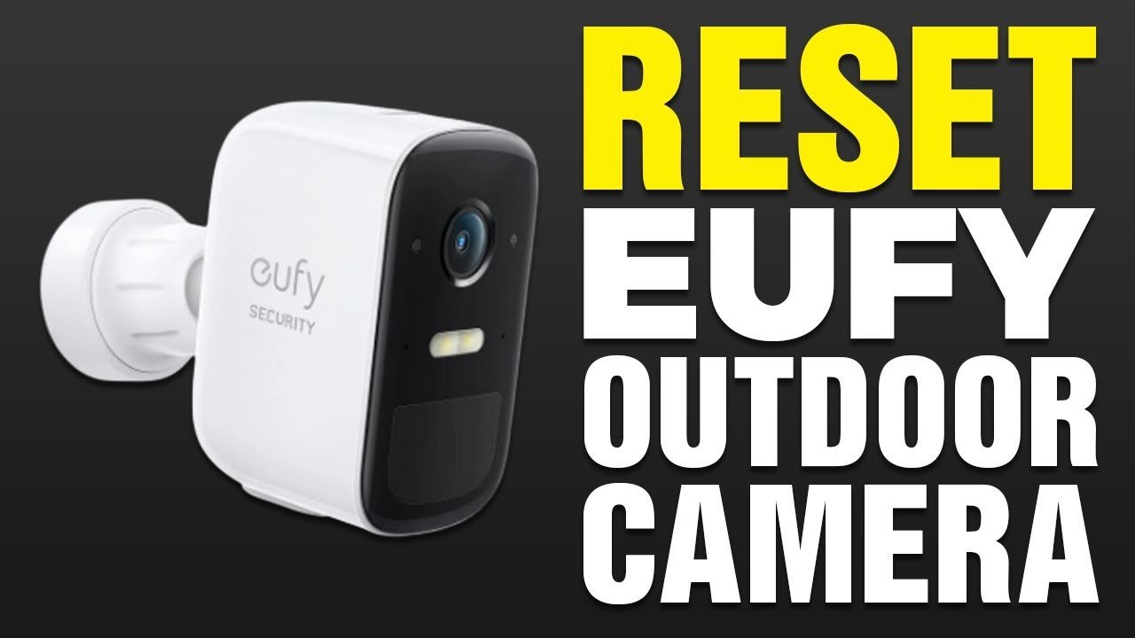 A finger pressing a small reset button on the back of a security camera.