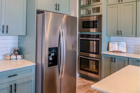 Finger pressing the filter reset button on a stainless steel refrigerator door.