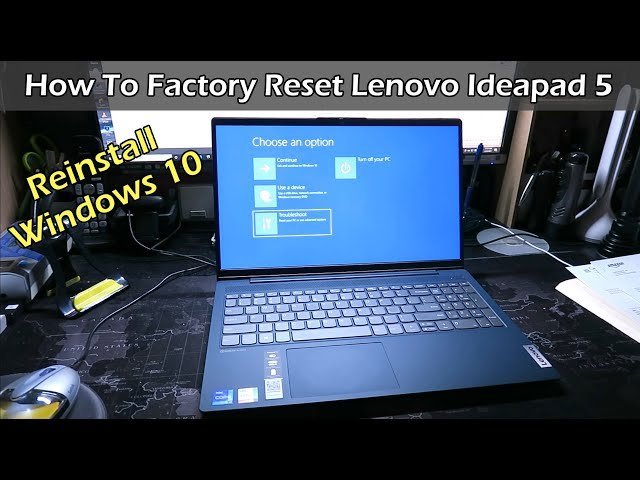 Essential tools for resetting a Lenovo IdeaPad arranged neatly on a wooden desk.