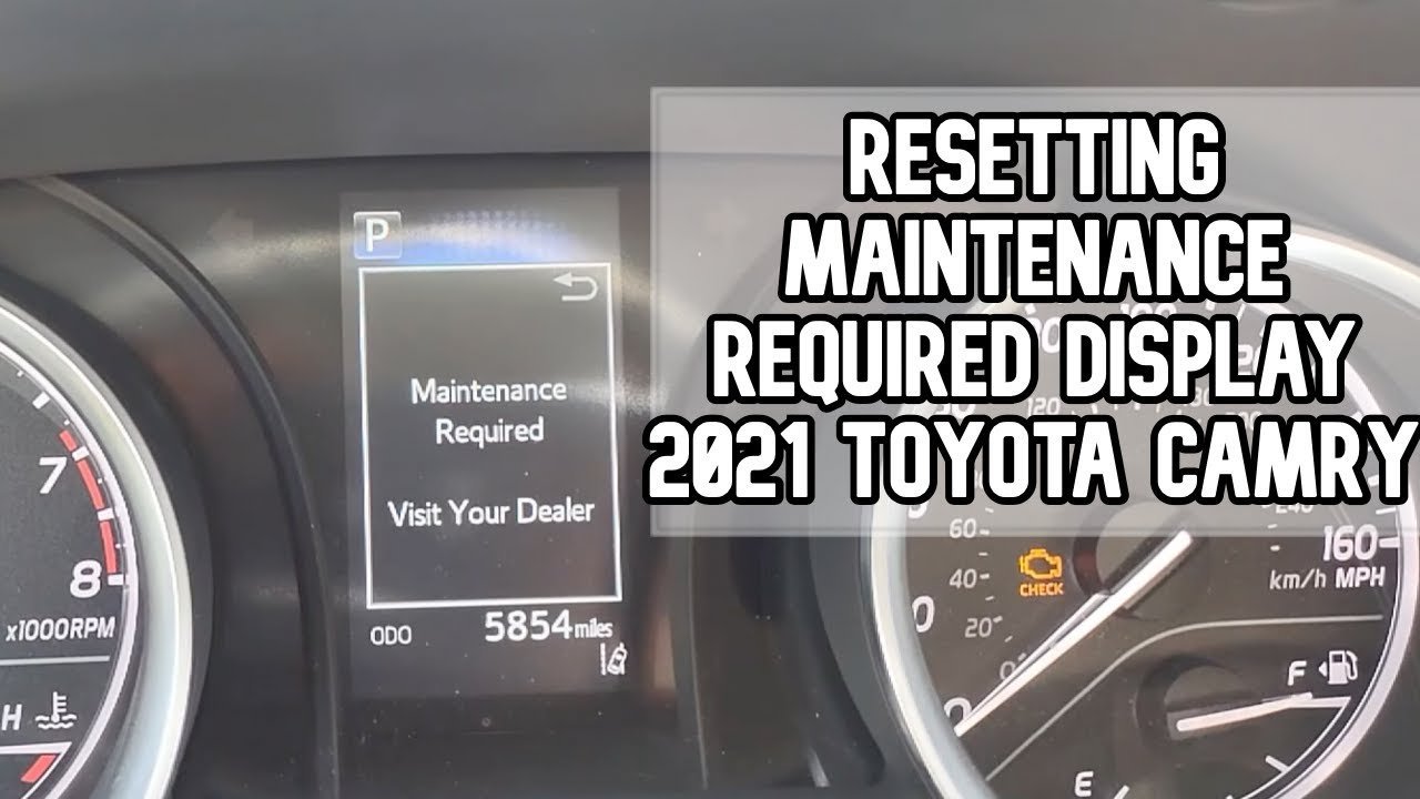 A driver pressing the engine start button to reset the Toyota maintenance light.