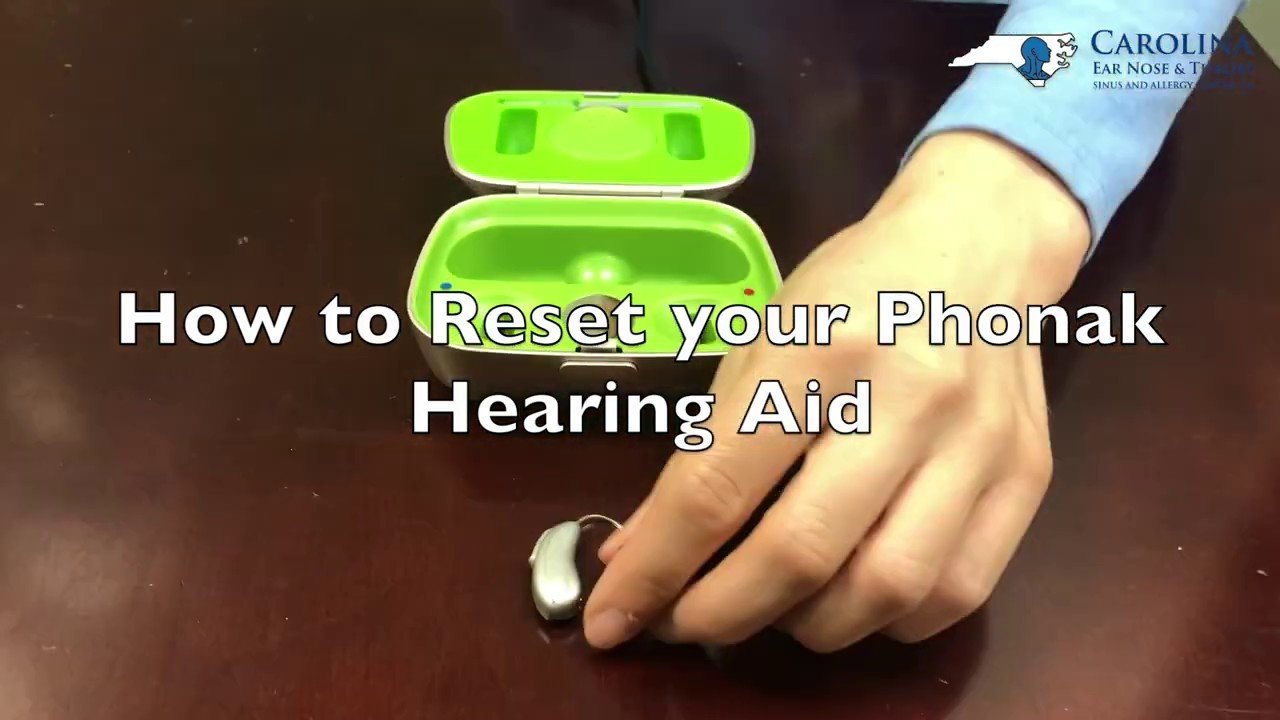 Close up of fingers pressing the toggle switch on a Phonak hearing aid.