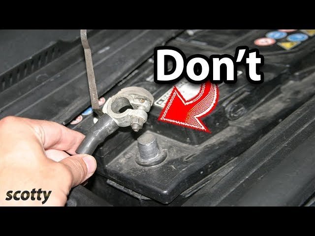 A wrench held carefully near a car battery to avoid electrical hazards.
